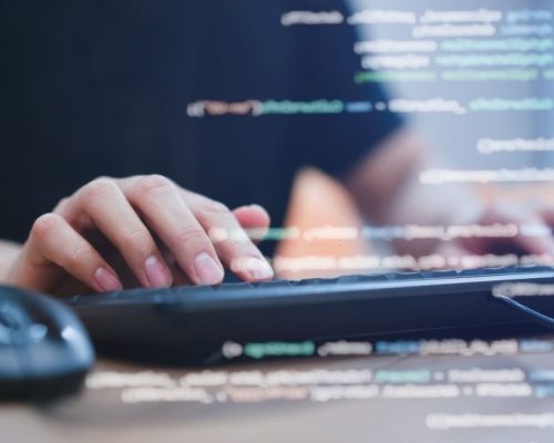 close up programmer student man hand typing on keyboard at computer desktop  to input code language into software for study bug and defect of system in classroom , development of technology concept