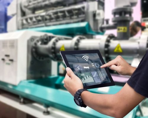 Hands holding tablet on blurred automation machine as background
