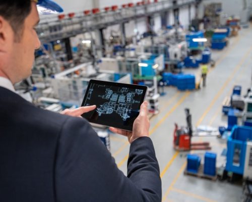 Manager examining engineering drawing on digital tablet in factory.